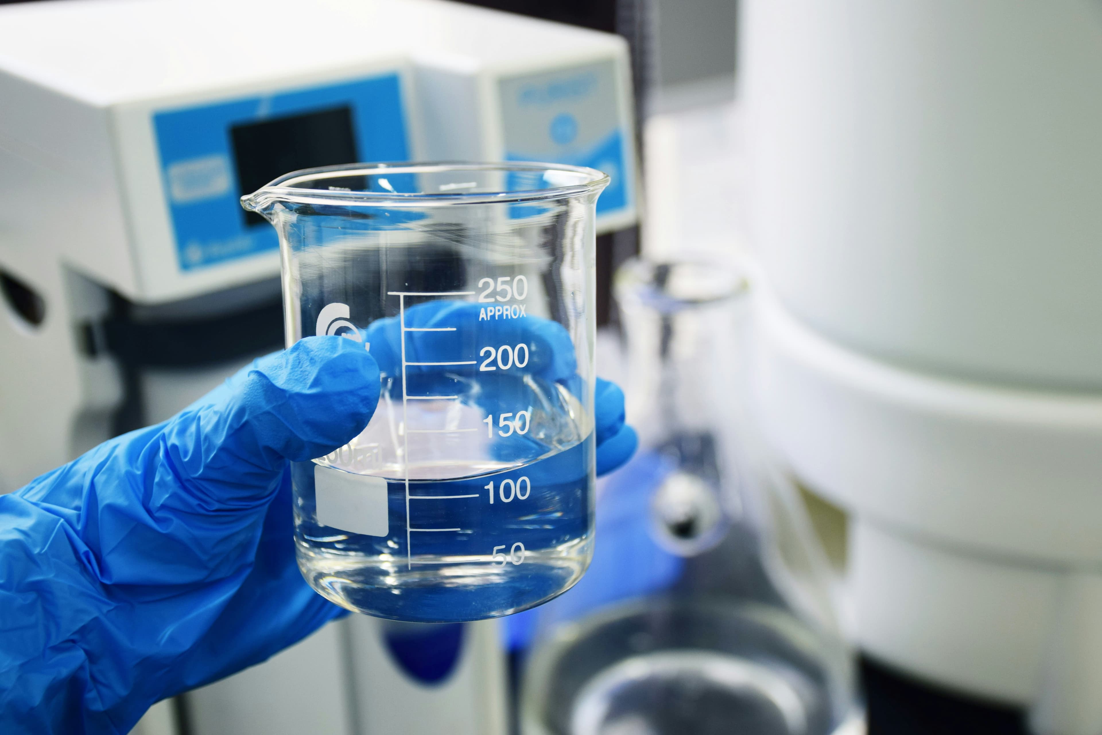 Analista de laboratório segurando béquer graduado para análise de água